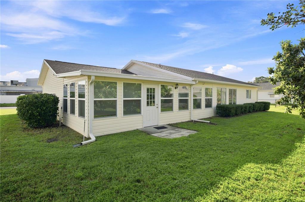 The exterior of a light yellow house features a large sunroom with many windows — 17960 SE 108TH COURT, SUMMERFIELD, FL