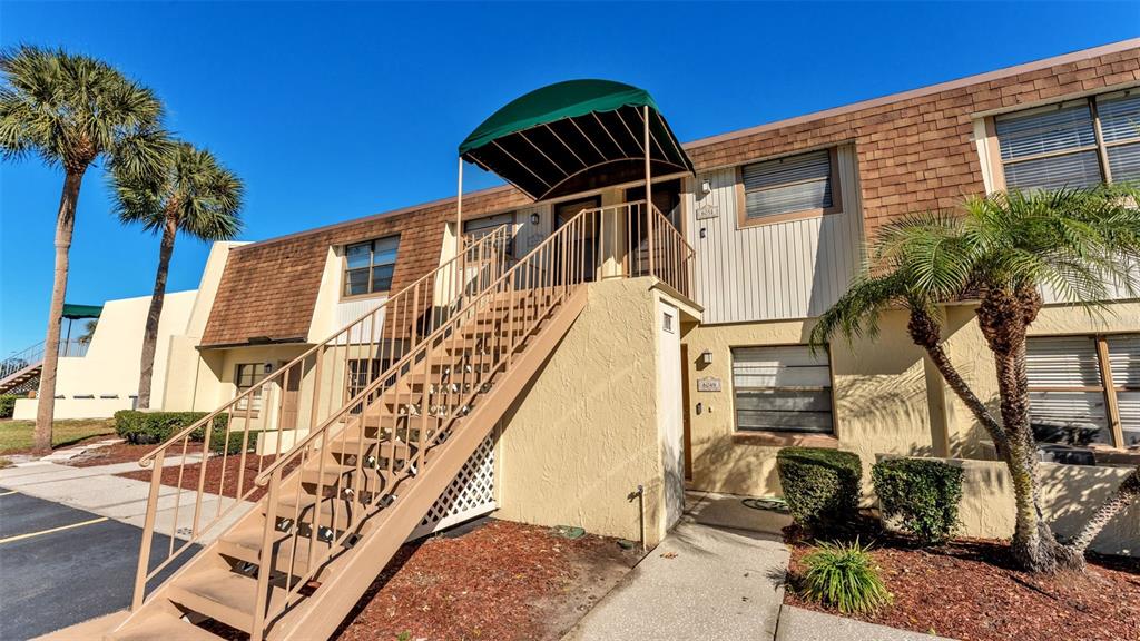 An exterior view of a two-story apartment building with a metal staircase and green awning — 6051 TOPHER TRAIL UNIT 6051, MULBERRY, FL