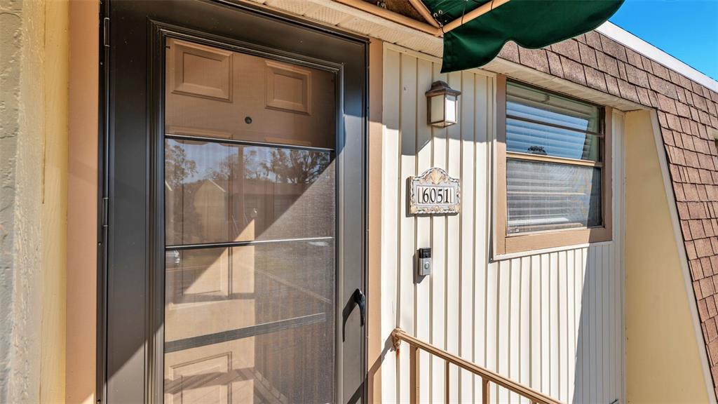 A front entrance features a dark storm door, a house number plaque, and a wall-mounted light — 6051 TOPHER TRAIL UNIT 6051, MULBERRY, FL