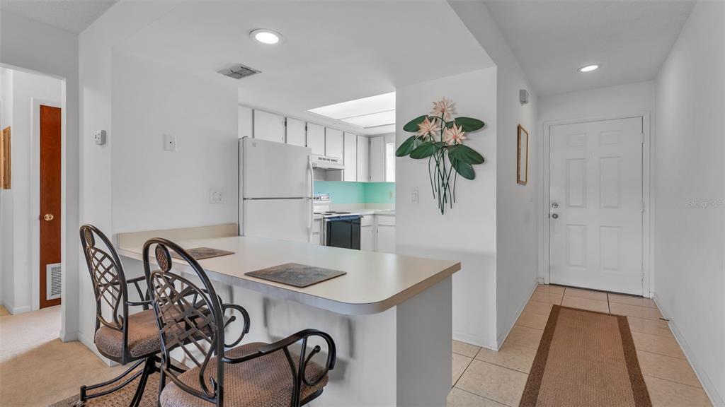 A kitchen with a breakfast bar, white cabinets, and a tiled entryway with a door — 6051 TOPHER TRAIL UNIT 6051, MULBERRY, FL