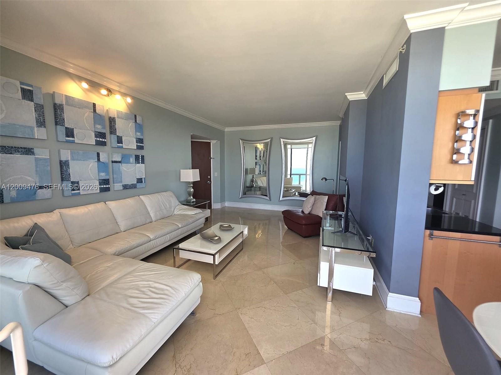 A living room features a white sectional sofa, marble floors, and two large wall mirrors — 6365 Collins Ave # 4311, Miami Beach FL 33141, MIAMI BEACH, FL