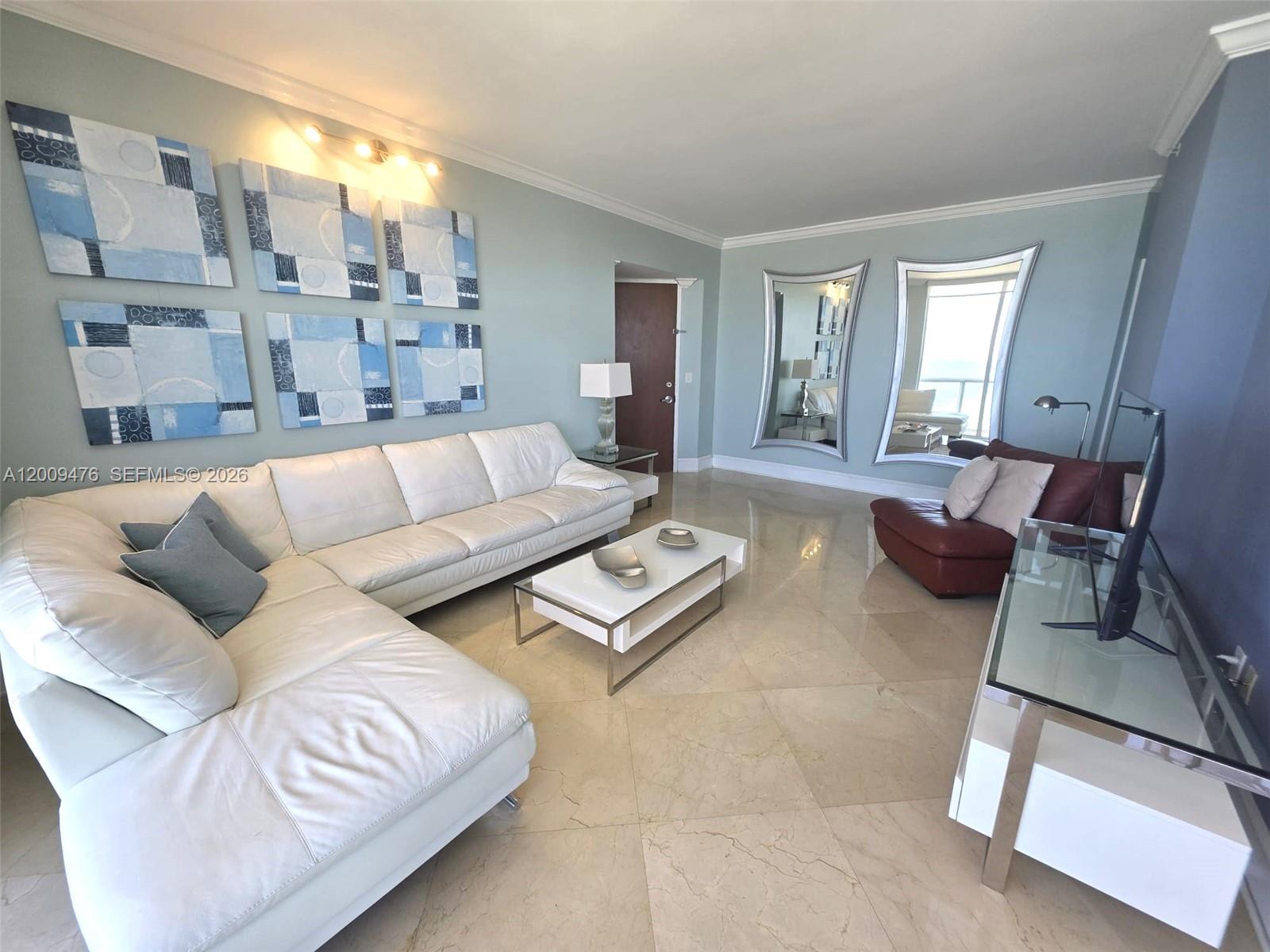 A living room features a white sectional sofa, a glass coffee table, and two mirrors — 6365 Collins Ave # 4311, Miami Beach FL 33141, MIAMI BEACH, FL