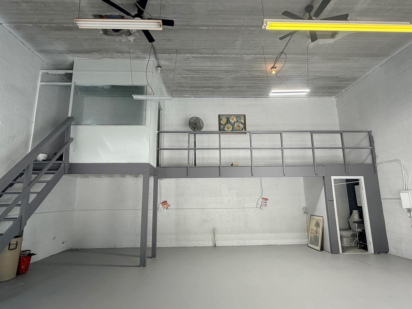 An industrial-style room features a gray mezzanine level with stairs and a small bathroom — 1791 Blount Road # 922, Pompano Beach FL 33069, POMPANO BEACH, FL