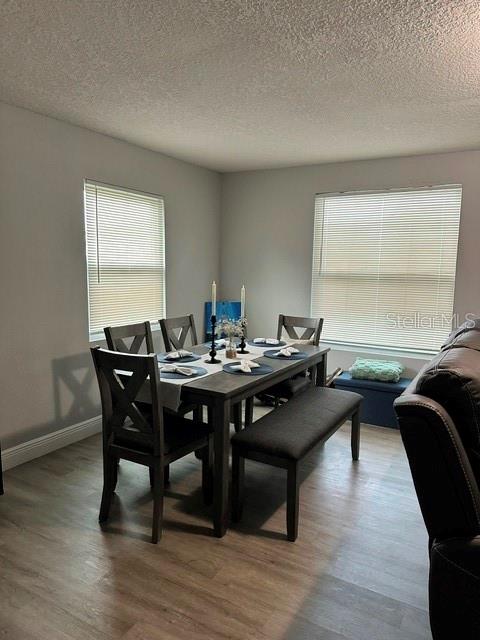 A dining room features a wooden table with chairs and a bench under two windows — 438 S HUDSON STREET, ORLANDO, FL
