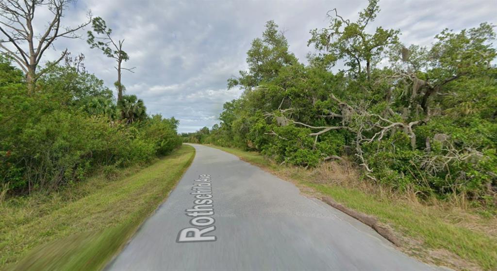 A paved road winds through a wooded area with dense green trees and vegetation — 14713 ROTHSCHILD AVENUE, PORT CHARLOTTE, FL
