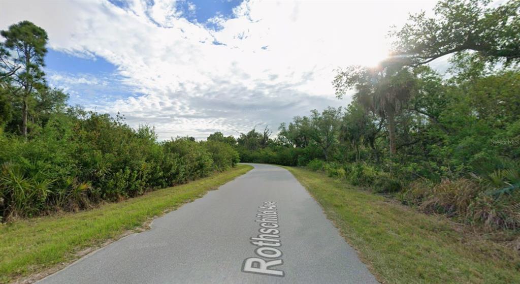 A paved road winds through a wooded area under a cloudy sky — 14713 ROTHSCHILD AVENUE, PORT CHARLOTTE, FL