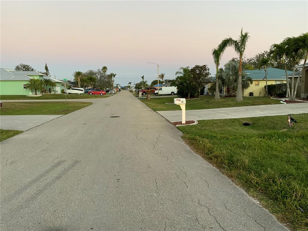 A residential street view featuring houses, palm trees, and parked vehicles under a clear sky — 312 SE 19TH LANE, CAPE CORAL, FL