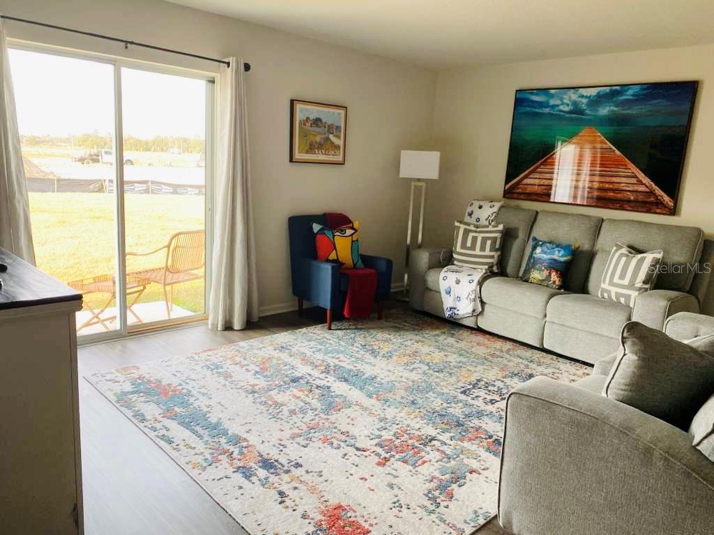 A living room features a gray sofa, a blue accent chair, and a large area rug — 2295 NW 25TH LANE, OCALA, FL