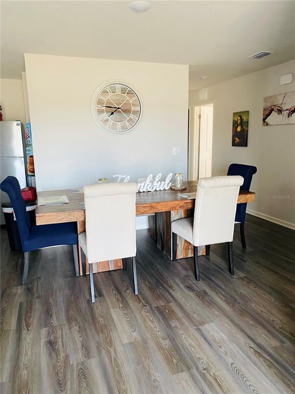 A dining room features a wooden table, four chairs, and a wall-mounted clock — 2295 NW 25TH LANE, OCALA, FL
