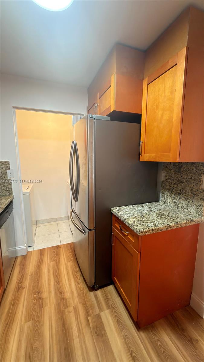 A kitchen features wood cabinets, granite countertops, a stainless steel refrigerator, and wood-look flooring — 469 NE 207th Ln # 101, Miami FL 33179, MIAMI, FL