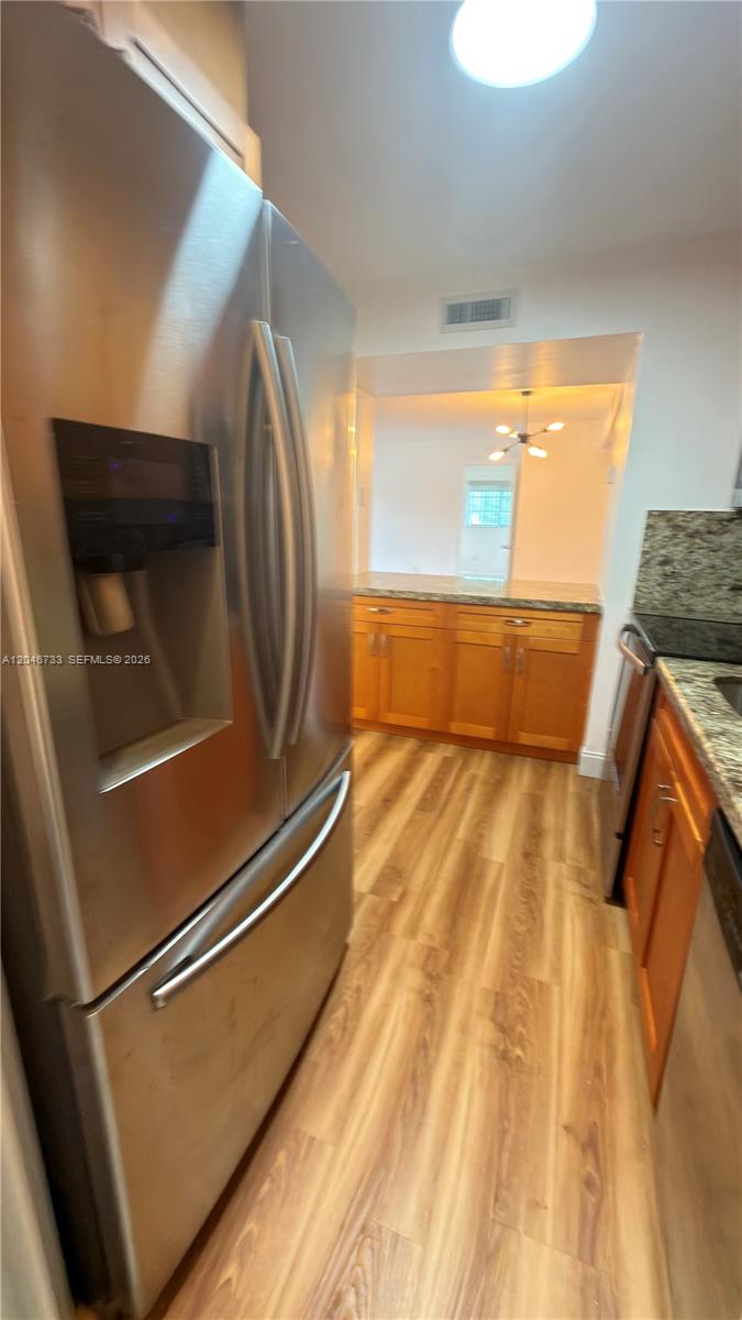 A kitchen features stainless steel appliances, wood cabinets, and light-colored wood-look flooring — 469 NE 207th Ln # 101, Miami FL 33179, MIAMI, FL