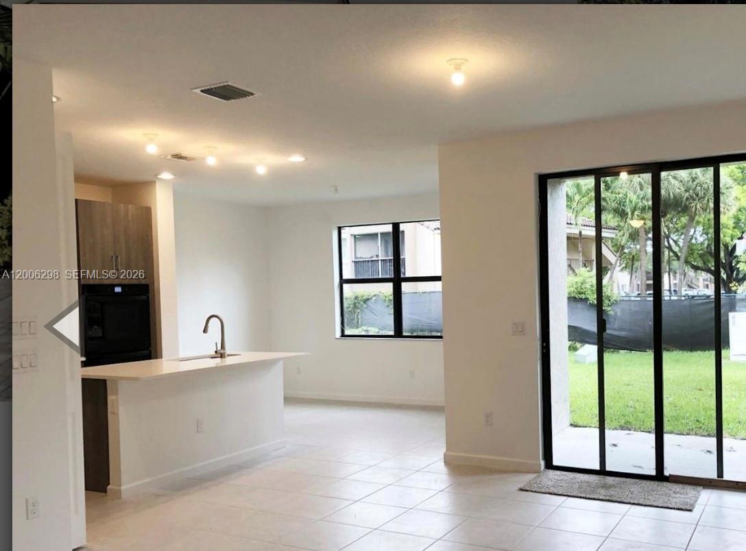 A kitchen with a breakfast bar, light tile floors, and a sliding glass door — 3525 NW 1st St, Pompano Beach FL 33069, POMPANO BEACH, FL