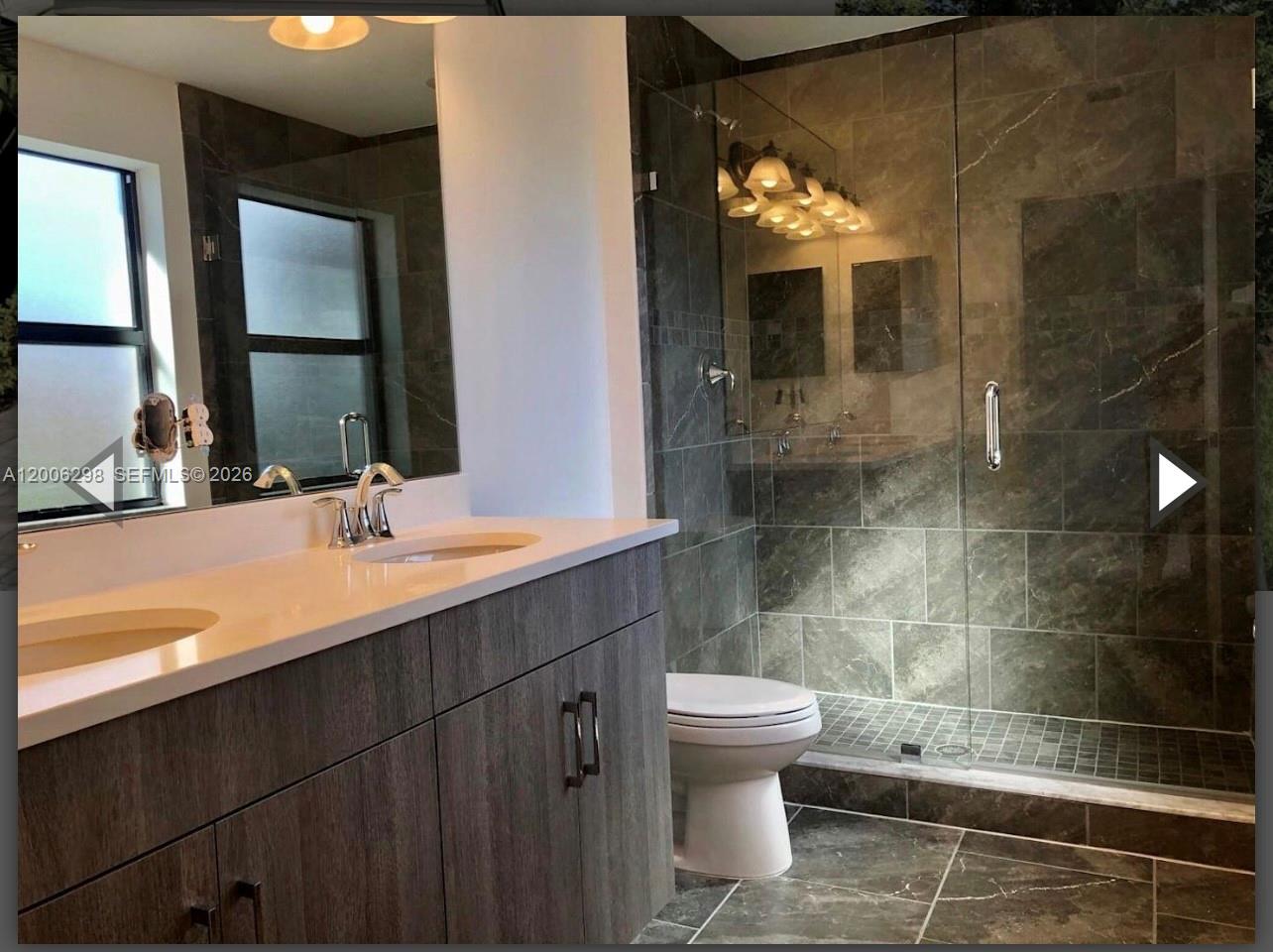 A bathroom features a double vanity with a white countertop and a glass-enclosed walk-in shower — 3525 NW 1st St, Pompano Beach FL 33069, POMPANO BEACH, FL