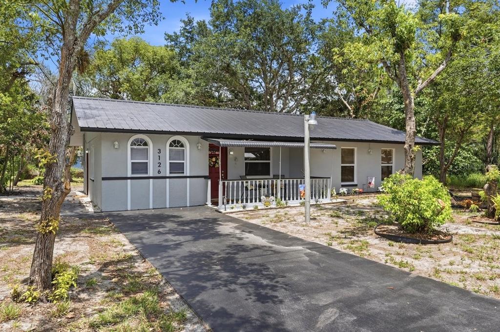 A single-story house with a metal roof, gray siding, and a front porch — 3126 MARLIN DRIVE, SEBRING, FL