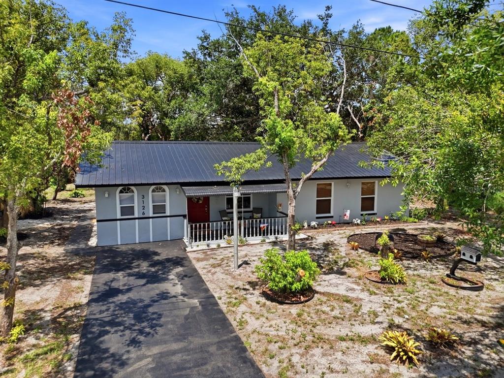 A single-story house with a black metal roof, gray siding, and a front porch — 3126 MARLIN DRIVE, SEBRING, FL