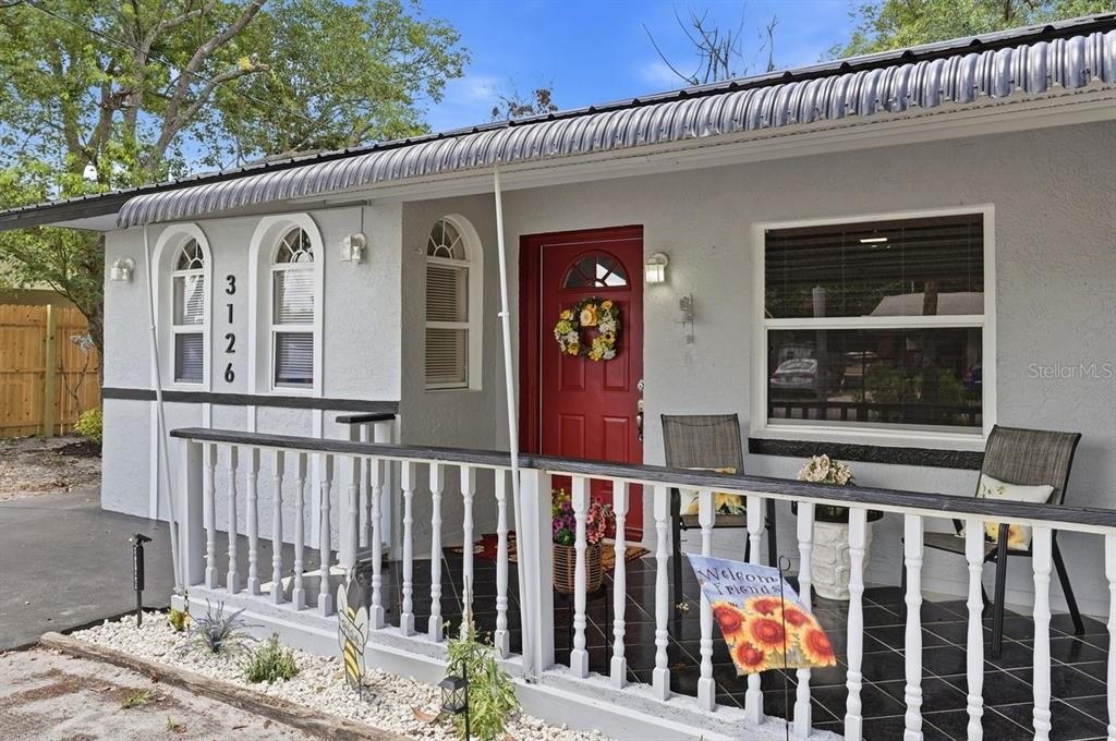 A house exterior features a red front door, a covered porch, and white railings — 3126 MARLIN DRIVE, SEBRING, FL