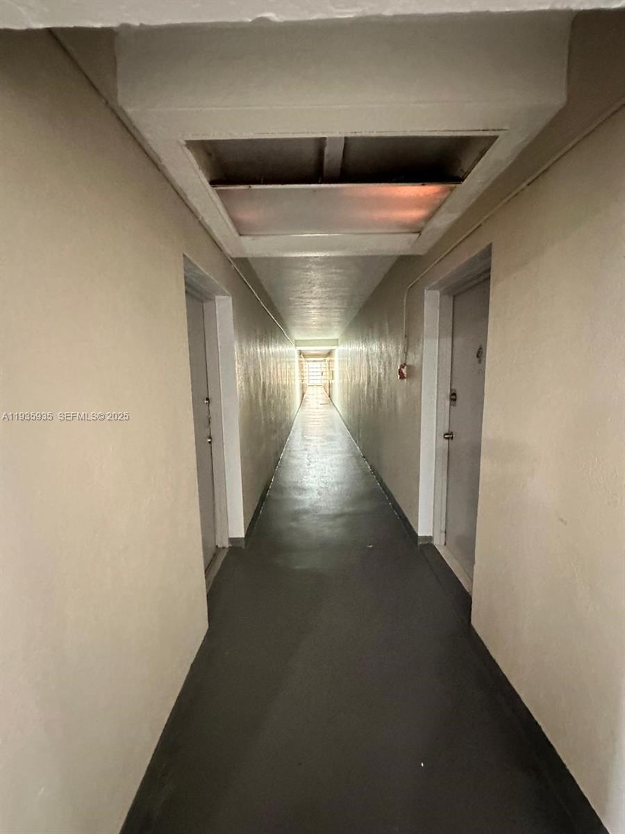 A long, narrow apartment hallway features beige walls, gray doors, and a recessed ceiling light — 1875 W 56th St # 301, Hialeah FL 33012, HIALEAH, FL