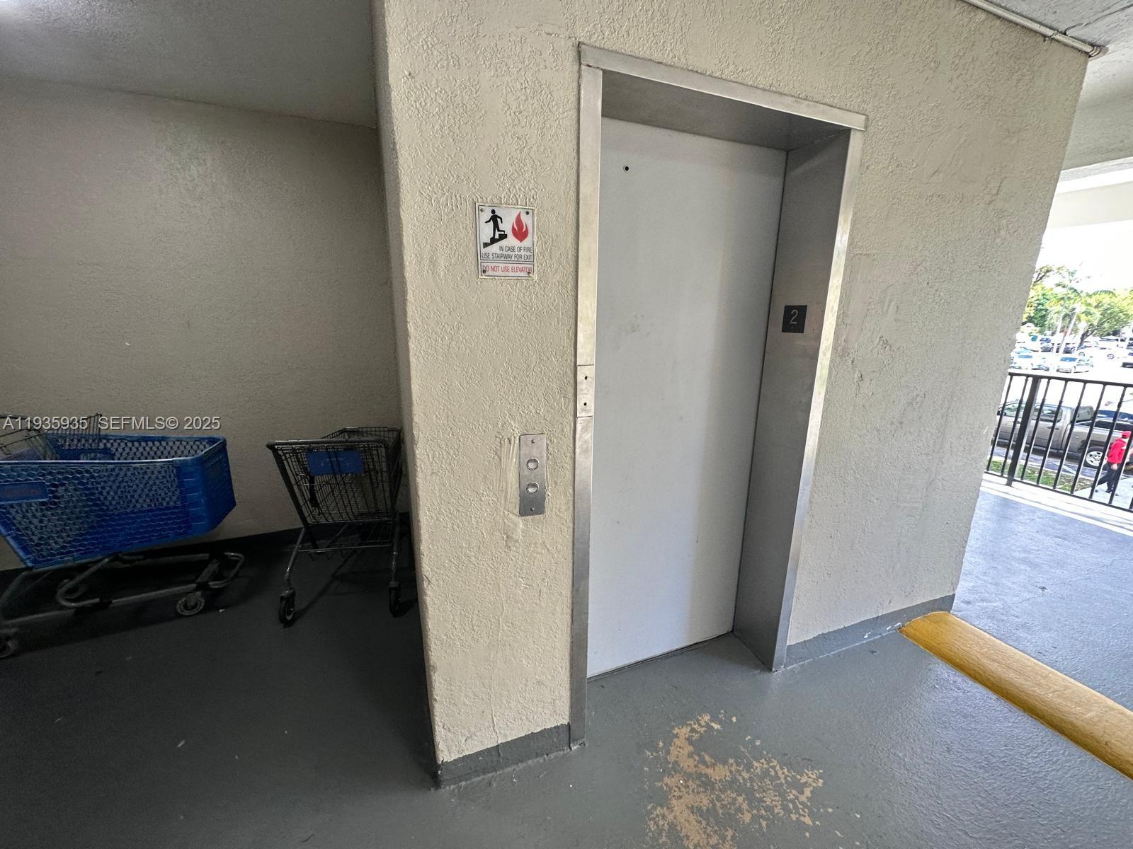 An elevator door is located in a hallway with two shopping carts nearby — 1875 W 56th St # 301, Hialeah FL 33012, HIALEAH, FL