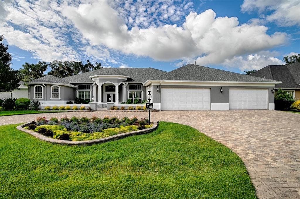 A single-story house with a gray exterior, a paved driveway, and a landscaped front yard — 1792 LAKE MIONA DRIVE, THE VILLAGES, FL