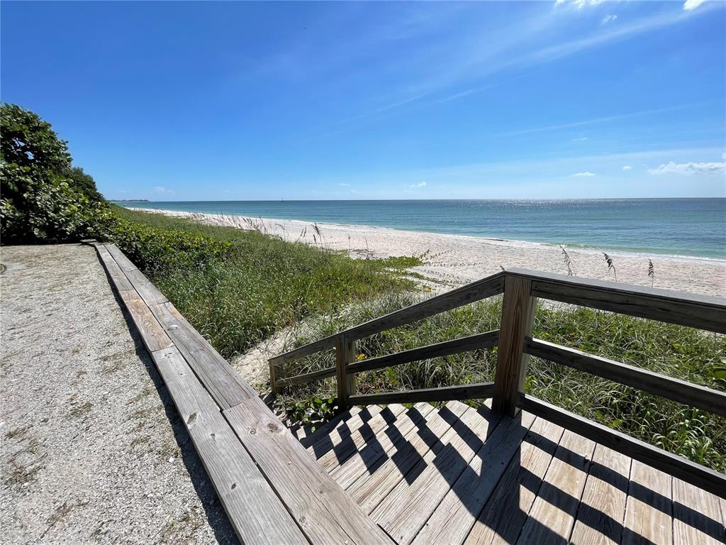 A wooden staircase leads from a gravel path down to a sandy beach and ocean — 2709 CASEY KEY ROAD, NOKOMIS, FL