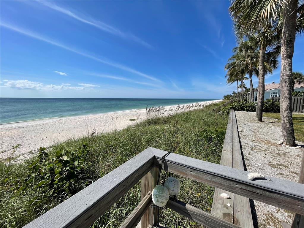 A wooden deck railing overlooks a grassy dune, sandy beach, and the ocean — 2709 CASEY KEY ROAD, NOKOMIS, FL