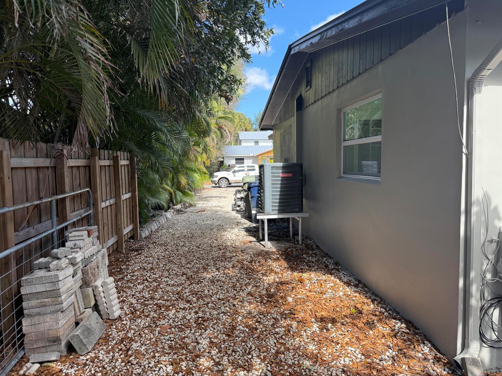 A gravel side yard features a Goodman air conditioning unit and a wooden fence — 507 SW North River Point Drive, Stuart FL 34994, STUART, FL