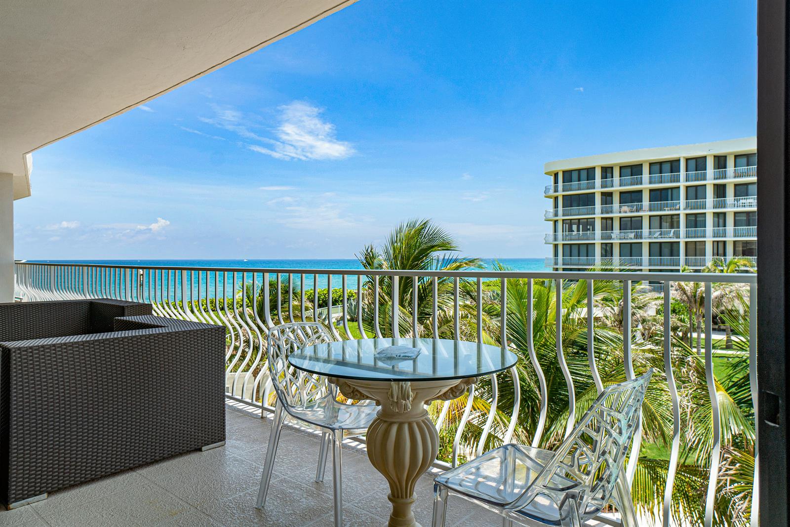 A balcony with a glass table, two transparent chairs, and a view of the ocean — 2000 S Ocean Boulevard # 208n, Palm Beach FL 33480, PALM BEACH, FL