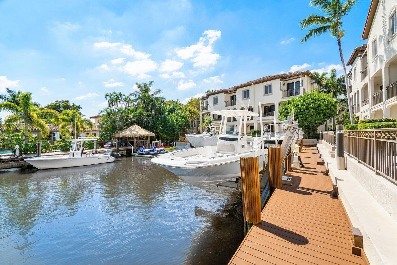 A boat lift holds a white motorboat next to a wooden dock on a canal — 3018 Waterside Circle, Boynton Beach FL 33435, BOYNTON BEACH, FL