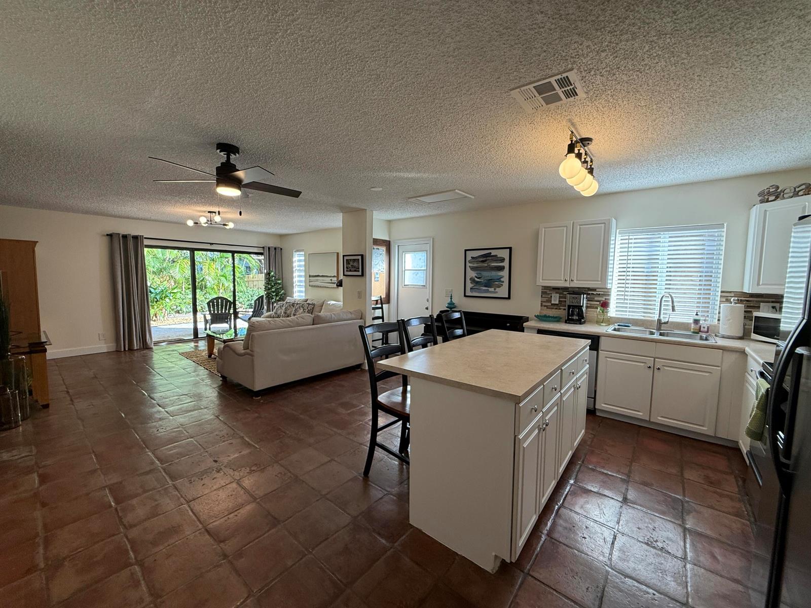 An open-concept kitchen and living area with tile floors, a center island, and sliding doors — 801 NE 2nd Avenue, Delray Beach FL 33444, DELRAY BEACH, FL