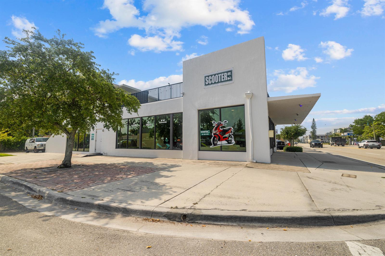 A white commercial building with large glass windows and a scooter decal on the exterior — 1914 N Dixie Highway, FL 33460, FL
