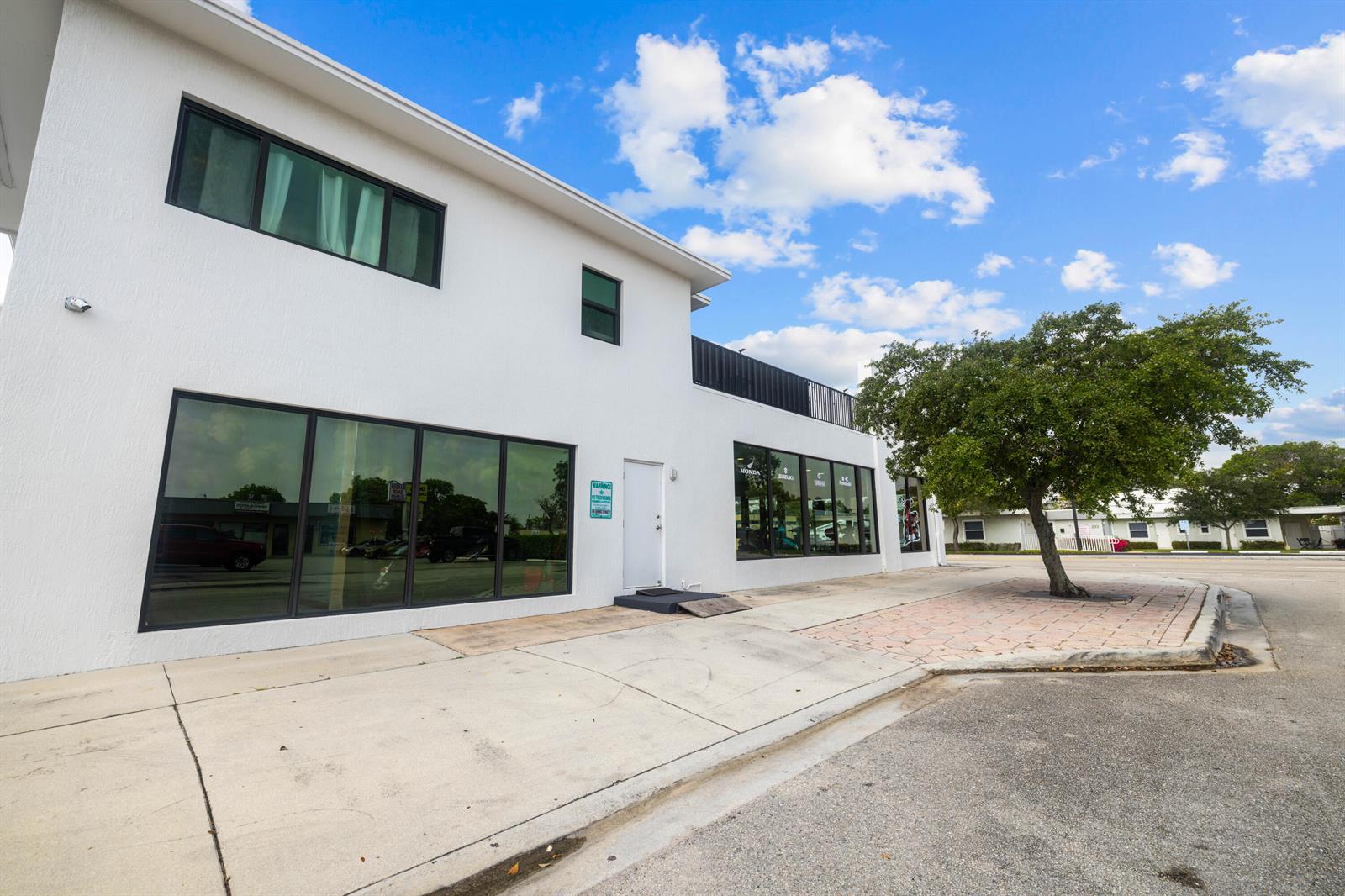A white two-story commercial building with large glass windows and a tree in front — 1914 N Dixie Highway, FL 33460, FL