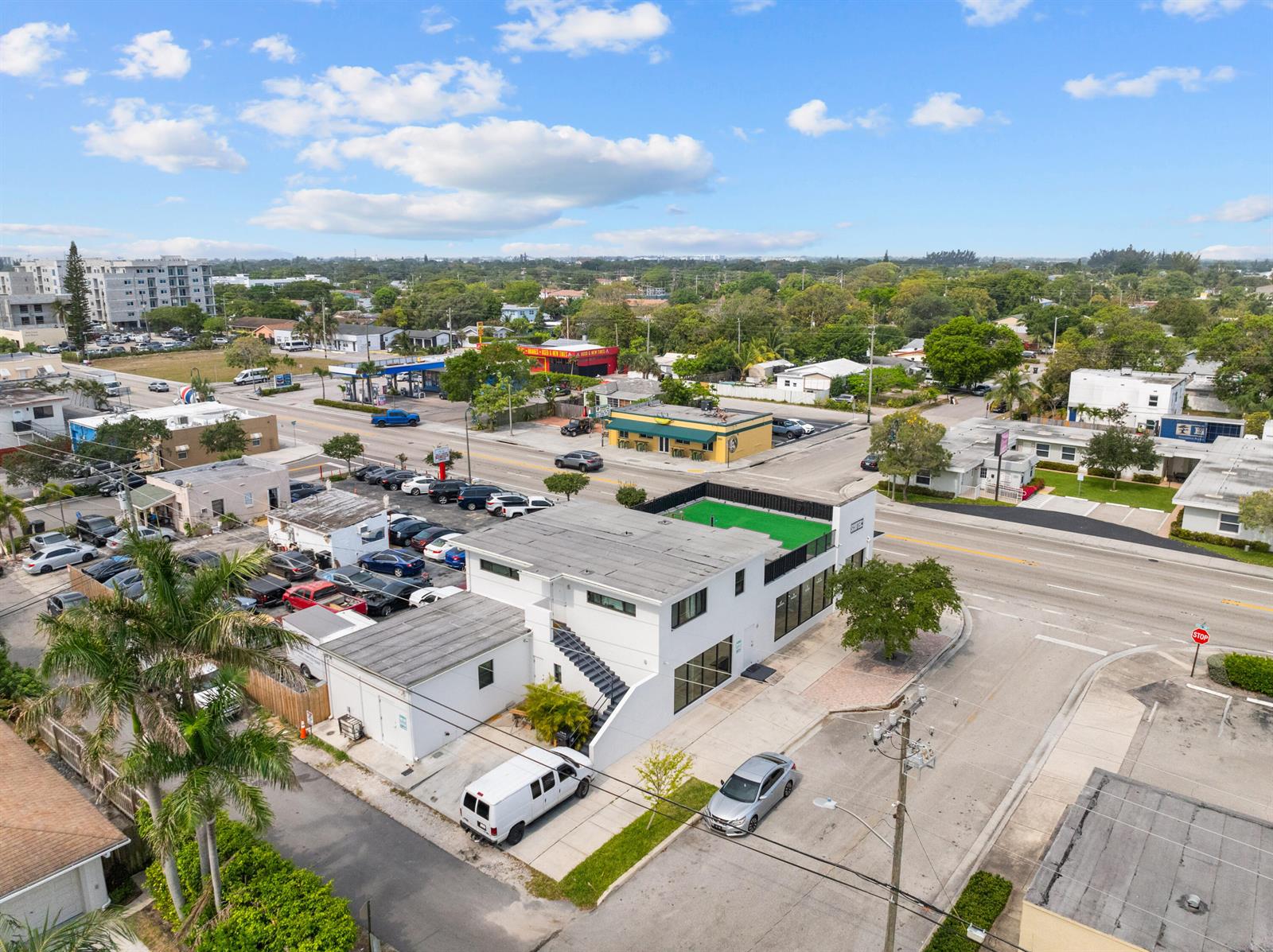 An aerial view shows a white commercial building with a rooftop terrace and parking lot — 1914 N Dixie Highway, FL 33460, FL