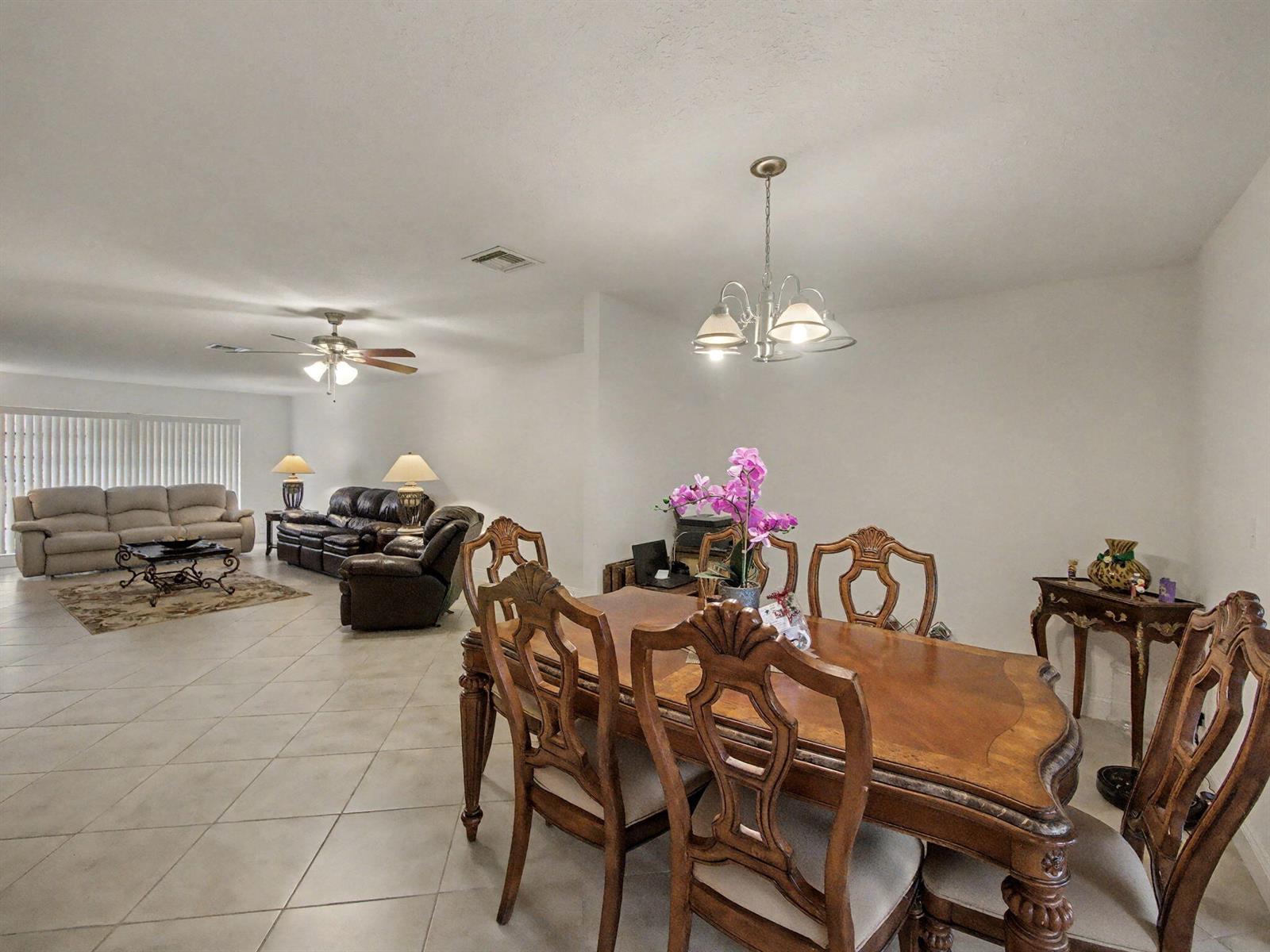 A dining area with a wooden table and chairs sits in front of a living room — 4759 Storkwood Terrace # A, Boynton Beach FL 33436, BOYNTON BEACH, FL