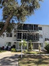 A three-story apartment building with screened balconies and a large tree in the foreground — 5906 17TH STREET W UNIT C35, BRADENTON, FL