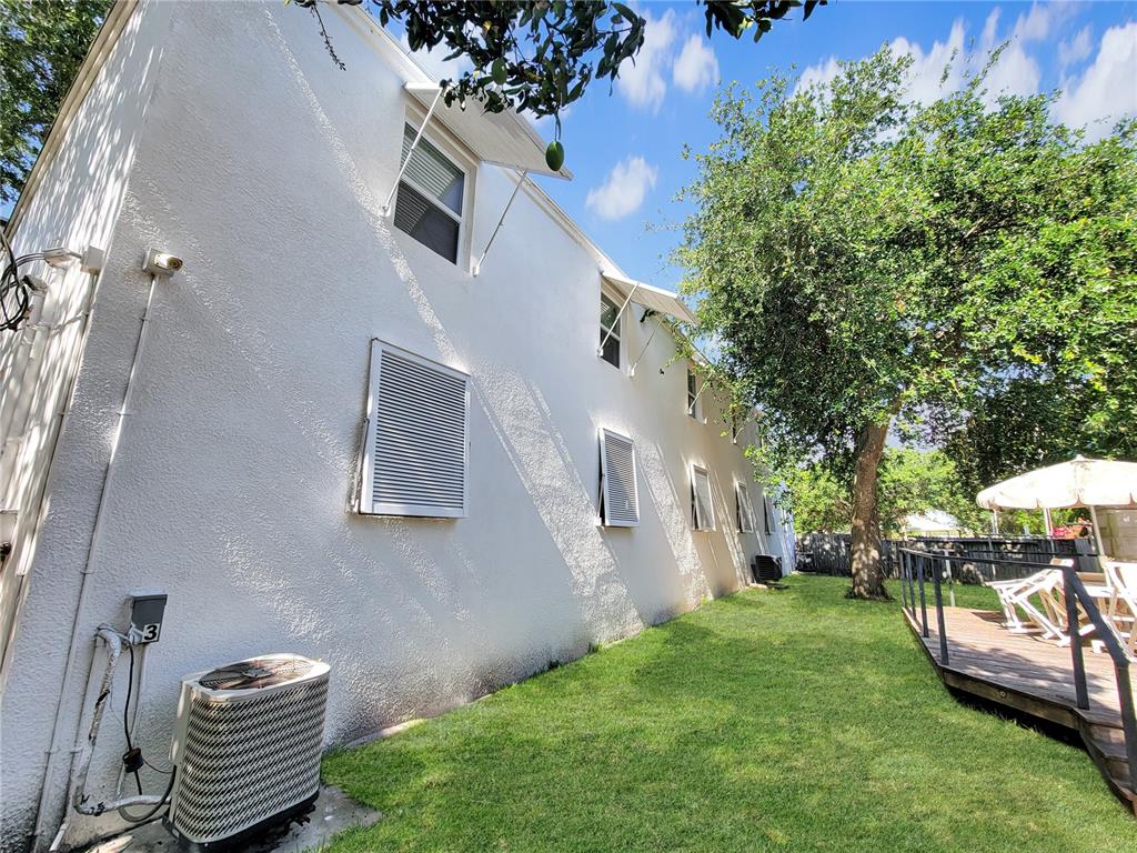 A white stucco exterior wall with multiple windows, awnings, and an air conditioning unit — 404 HARRISON AVENUE, CAPE CANAVERAL, FL