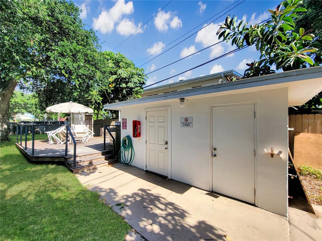 A white utility building with two doors stands next to a wooden deck with chairs — 404 HARRISON AVENUE, CAPE CANAVERAL, FL