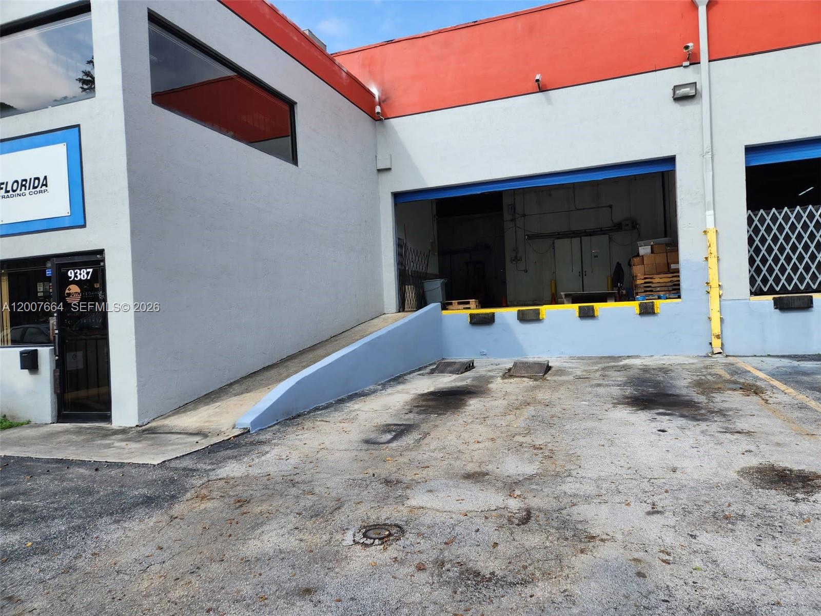 The exterior of a commercial building features a loading dock, a ramp, and a glass door — 9387 NW 13th St # 7, Doral FL 33172, DORAL, FL