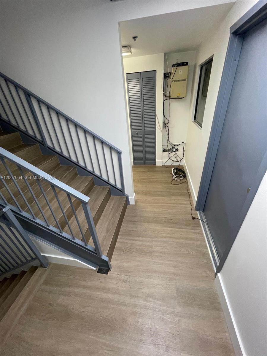 A staircase with gray railings leads to a hallway with wood-look flooring and a closet — 9387 NW 13th St # 7, Doral FL 33172, DORAL, FL
