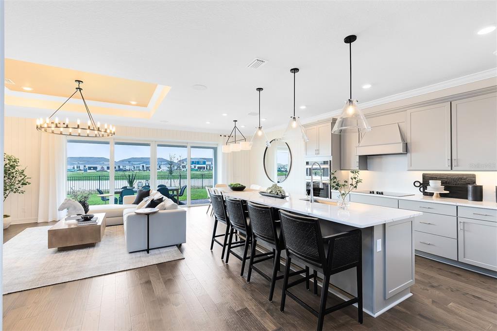 A modern open-concept kitchen and living area with a large island, pendant lights, and sliding doors — 2216 BRANCHED OAK ROAD, ST CLOUD, FL