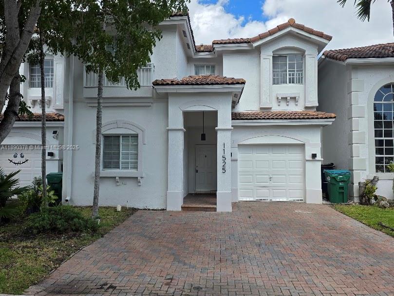 A two-story white stucco house features a brick driveway and a single-car garage — 11525 NW 71st St # 11525, Doral FL 33178, DORAL, FL