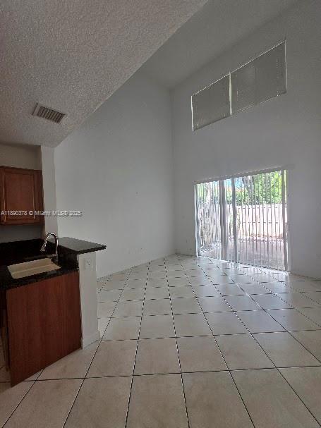 A kitchen with dark countertops and a dining area featuring tile floors and high ceilings — 11525 NW 71st St # 11525, Doral FL 33178, DORAL, FL