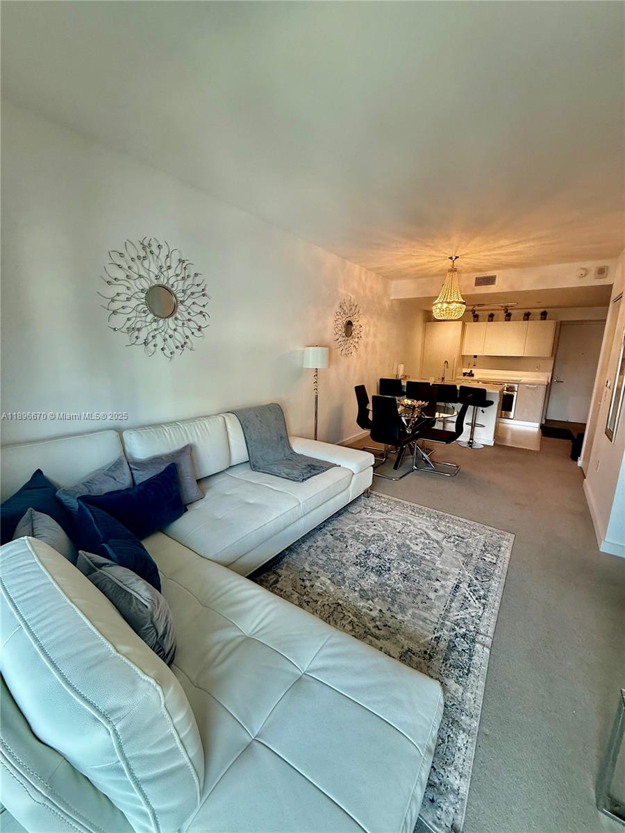 A white sectional sofa sits on a patterned rug in an open-concept living and dining area — 501 NE 31st St # 602, Miami FL 33137, MIAMI, FL