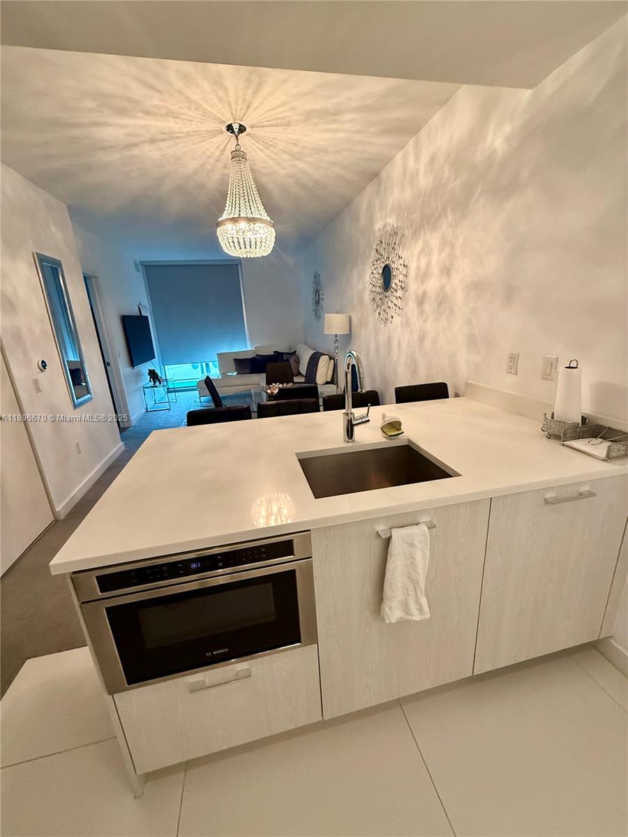 A kitchen island with a built-in microwave and sink overlooks a living area — 501 NE 31st St # 602, Miami FL 33137, MIAMI, FL
