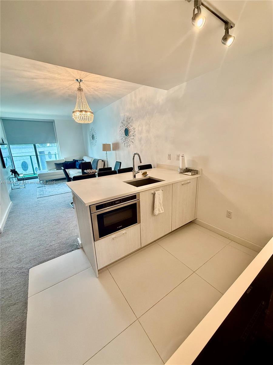 A kitchen island with a built-in microwave and sink overlooks a living area with carpet — 501 NE 31st St # 602, Miami FL 33137, MIAMI, FL