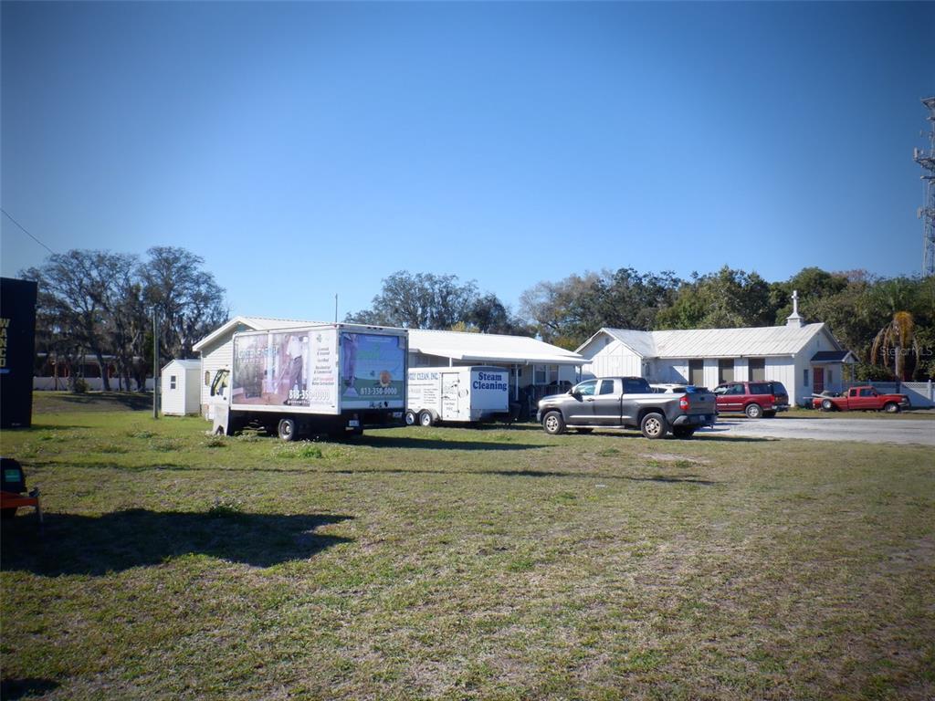 A grassy lot features a commercial box truck, a utility trailer, and two small buildings — 2239 OLD GUNN HIGHWAY, ODESSA, FL