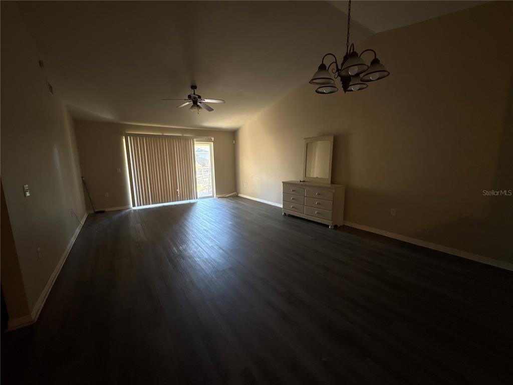 A large, empty room features dark wood-look flooring, a ceiling fan, and a dresser — 13912 SW 61ST CIRCLE, OCALA, FL