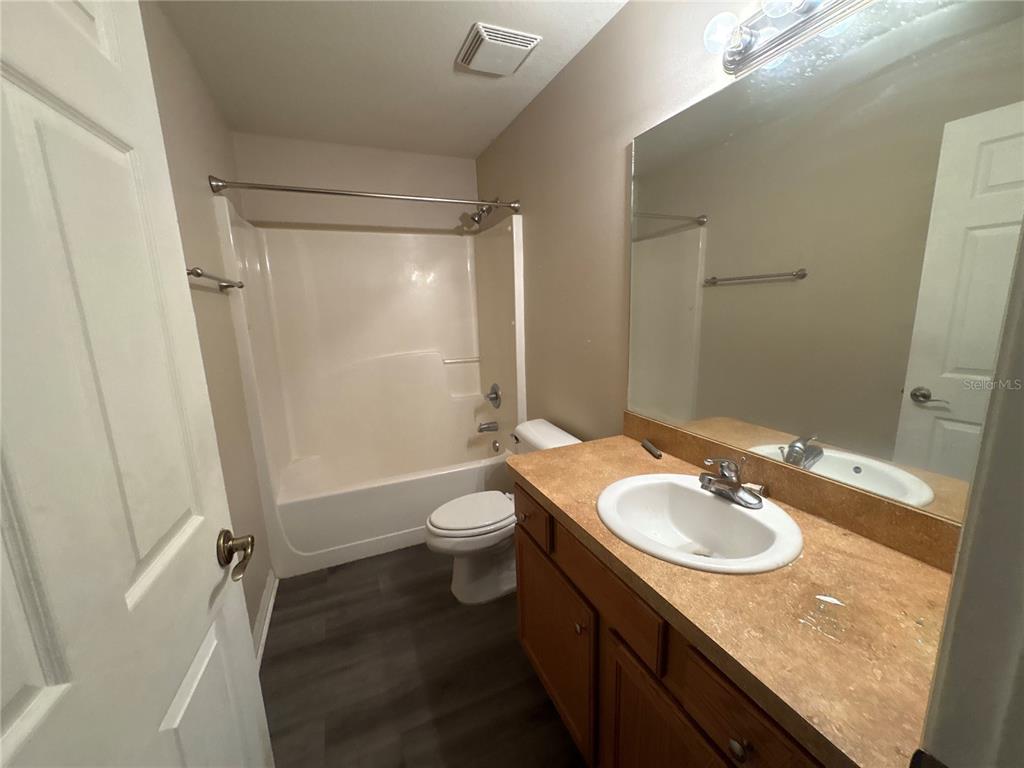 A bathroom features a vanity with a tan countertop, a toilet, and a shower-tub combo — 13912 SW 61ST CIRCLE, OCALA, FL