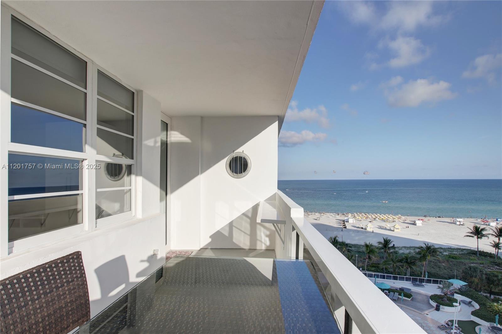 A balcony with a glass-topped table overlooks a sandy beach and the ocean — 100 Lincoln Rd # 940, Miami Beach FL 33139, MIAMI BEACH, FL