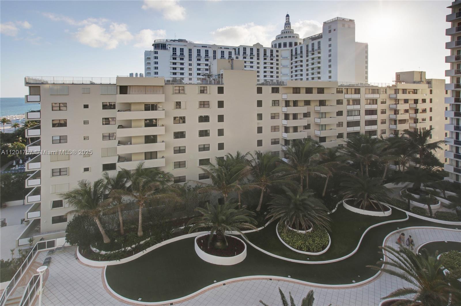 An exterior view shows a multi-story apartment building with a landscaped courtyard and palm trees — 100 Lincoln Rd # 940, Miami Beach FL 33139, MIAMI BEACH, FL