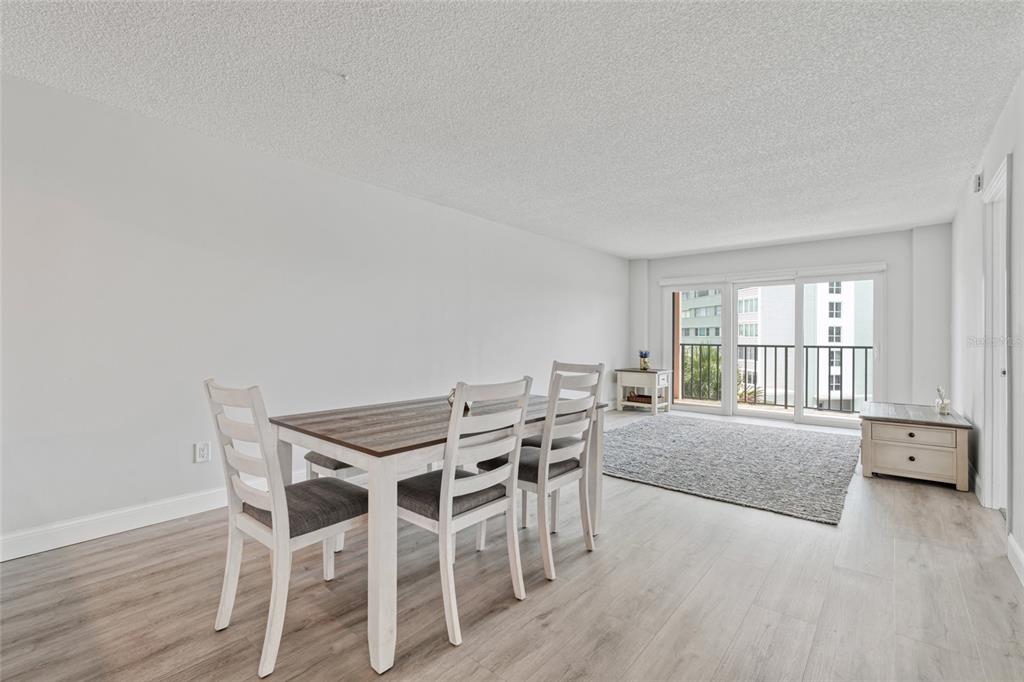 A dining area with a wooden table and chairs sits in a room with light flooring — 51 ISLAND WAY UNIT 411, CLEARWATER BEACH, FL